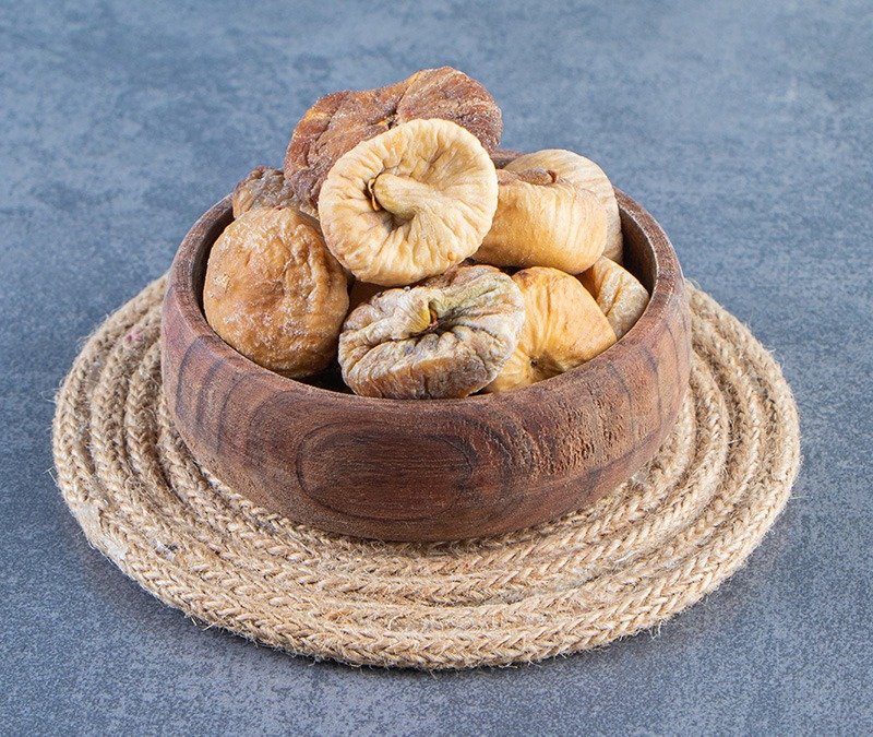 various dried fruits in a bowl on a trivet , on the marble background